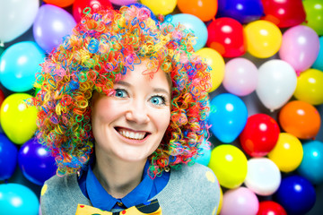 Fototapeta na wymiar Frau in Karnevalstimmung auf einem bunten Hintergrund aus Luftballons 