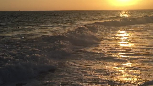 Surfisti su onde californiane al tramonto