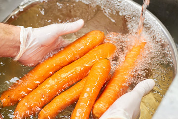 Dipping carrots into water. Rinsing carrots in bowl of water. Washing fresh carrots vegetables.