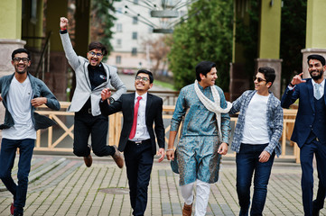 Group of six south asian indian mans in traditional, casual and business wear walking dancing and having fun together.