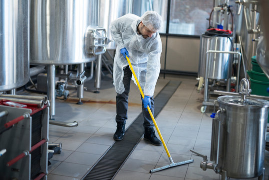 Industrial cleaning service. Industrial worker cleaning production plant floor.