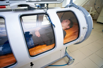 the guy in the black T-shirt lies in the hyperbaric chamber, oxygen therapy, medical room