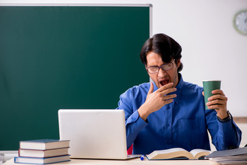 Young male teacher in front of chalkboard  