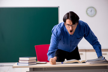 Young male teacher in front of chalkboard  