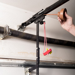 Man oils the quick release of a garage door opener to keep it working smoothly