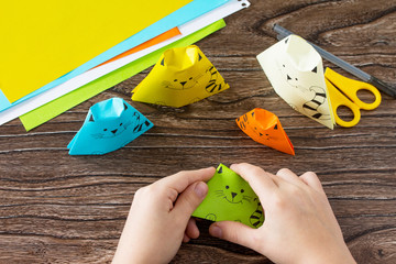 The child folds the parts various Origami toy made from paper puppets cat. Handmade. Project of...