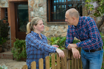 Man and woman communicate in a friendly way on the border of their farms