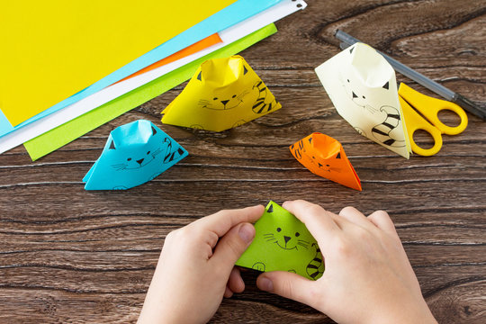 The child folds the parts various Origami toy made from paper puppets cat. Handmade. Project of children's creativity, handicrafts, crafts for kids.