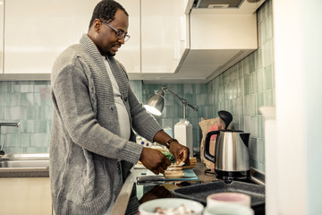 Caring loving husband making morning sandwiches in kitchen