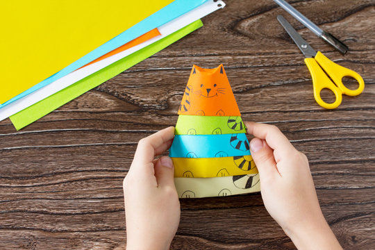 Origami toy made from paper puppets cat. Glue, scissors and paper on a wooden table. Children's art project craft for kids. Craft for children.