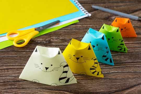 Origami toy made from paper puppets cat. Glue, scissors and paper on a wooden table. Children's art project craft for kids. Craft for children.