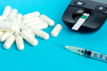 Glucometer, medication, syringe lie on a blue background.