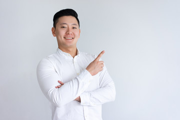 Positive Asian man pointing finger aside. Young guy recommending something. Advertisement concept....
