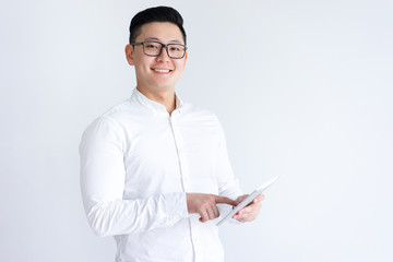 Smiling Asian man using tablet computer. Handsome young guy holding digital gadget. Technology concept. Isolated front view on white background.
