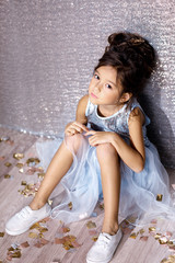 Fototapeta premium little child girl in dress sitting on the floor with confetti