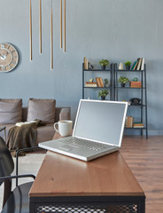 Fototapeta premium Close up wooden desk and computer, gold lamp and wooden clock, bookshelf and sofa.