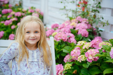 Fototapeta premium New life concept. Spring holiday. Summer. Mothers or womens day. Childrens day. Small baby girl. Little girl at blooming flower. Spring flowers. Childhood. happy girl. Summer relaxation