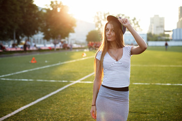 Beautiful girl posing for photo on sports playground at sunset