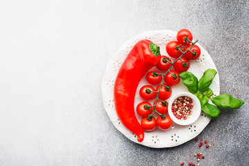 Ingredients for cooking. Cherry tomatoes, paprika, basil, pink pepper, sea salt, pasta on a light background. Top view. Copy space
