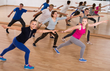 Teenage boys and girls with trainer stretching in dance hall