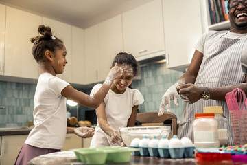 Father and two cute daughters having much fun while cooking pie