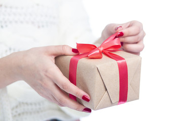 girl holding a present in hands, woman opening the box wrapped in craft paper on white isolated background, concept winter holiday