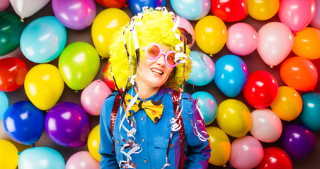 Fototapeta na wymiar Frau in Karnevalstimmung auf einem bunten Hintergrund aus Luftballons 