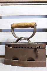Old iron, heated by hot coals. Located on the background of a wooden box.