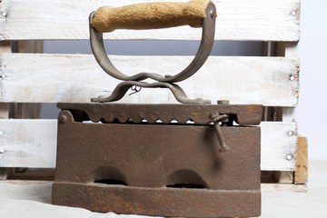 Old iron, heated by hot coals. Located on the background of a wooden box.