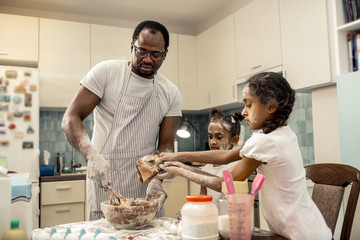 Father feeling happy cooking chocolate cupcakes with daughters