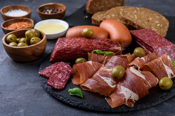 meat plate,  prosciutto and cheese, salami,  sausage and olives on gray  background