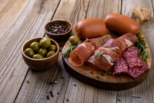 Prosciutto, salami and sausages on wooden background, meat platter