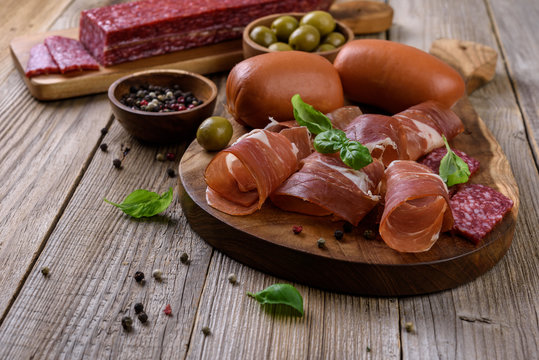 Prosciutto, salami and sausages on wooden background, meat platter