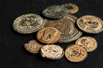 Pile of different ancient coins on black background