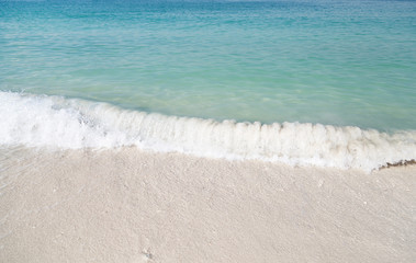 Soft wave of blue ocean on sandy beach.