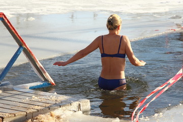 Beautiful walrus woman in swimsuit swimming in cold water in the ice hole in winter - winter...