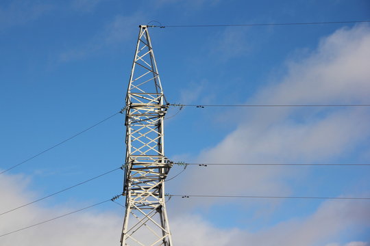 Clear energy, electricity - high steel mast of air  high-voltage power line against the blue sky with white clouds