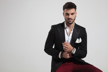 portrait of seated elegant man fixing his watch