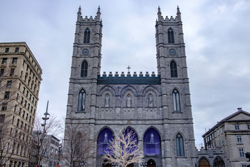 Fototapeta na wymiar Scenic beautiful view of Cathedral of Basilica of Notre Dame of Montreal. Depressive winter look of old catholic cathedral in the largest megapolis city of Quebec in Canada 