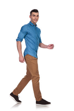 side view of handsome casual man wearing blue shirt walking