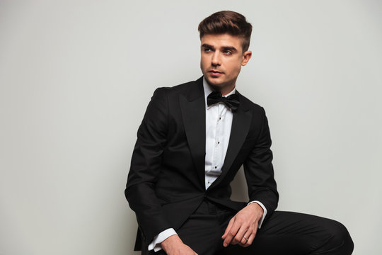 portrait of curious seated man wearing tuxedo looking to side