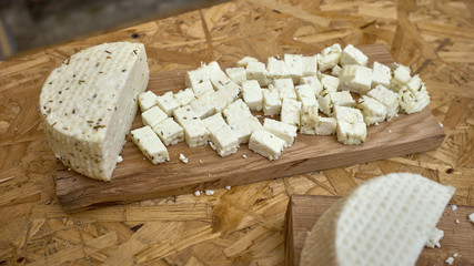 fresh raw aged delicatessen cheese with fennel on board for cutting of cheese on wooden table.