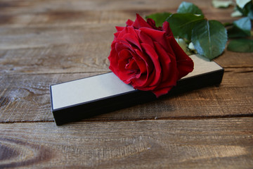 red rose and a box for a gift on a wooden rustic background with copy space for text