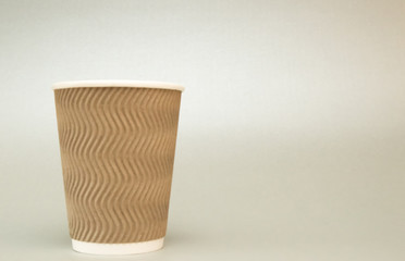 beige paper cup for coffee stands on a white background