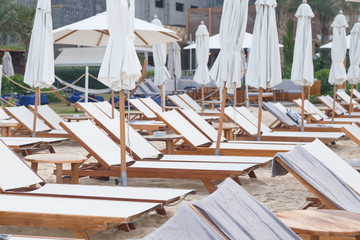 Empty beach chairs and umbrellas on sea shore. Not a season