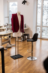 Elegant red jacket for women hanging on a dummy in a fashion studio