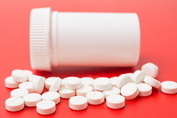 Pill bottle on red background. Painkiller or antibiotic abstract.