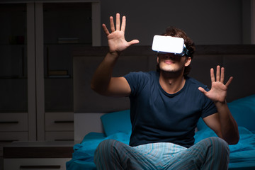 Young man playing computer games at night in bed