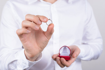 Closeup photo cropped picture of happy cheerful excited glad positive optimistic guy holding small little ring in hand with fingers isolated grey background