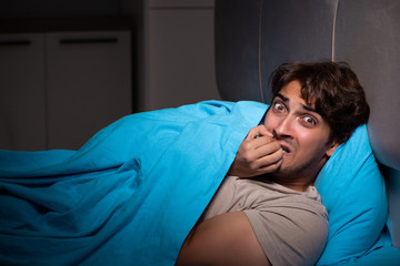 Young man scared in his bed having nightmares
